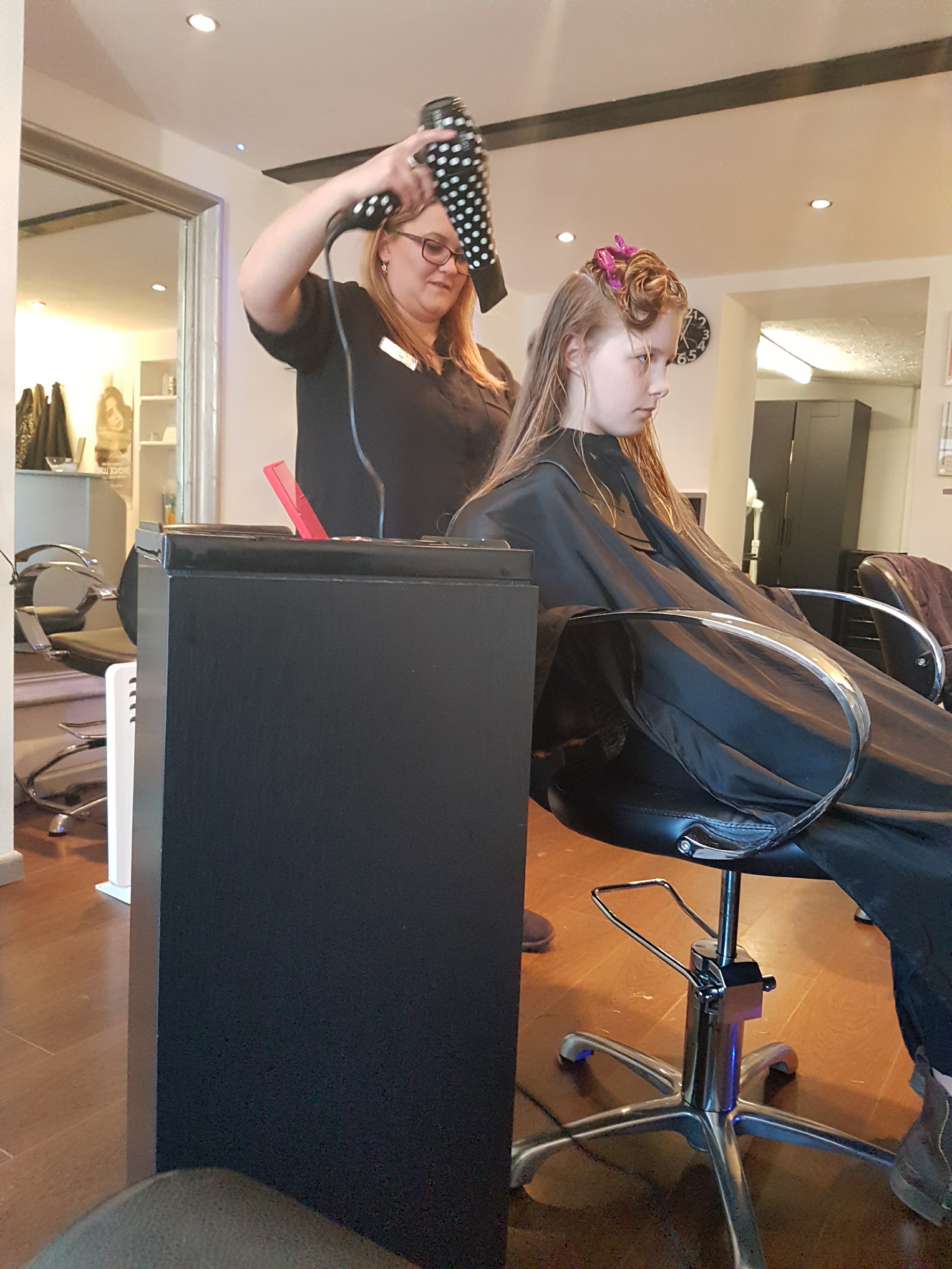 A stylist blow-dries a young customer's hair inside the Nu-Style salon
